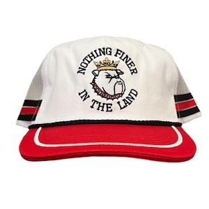 May include: White and red baseball cap with the text "NOTHING FINER IN THE LAND" and a bulldog graphic. The cap has a red brim, black rope detail, and mesh side panels with red and black stripes.