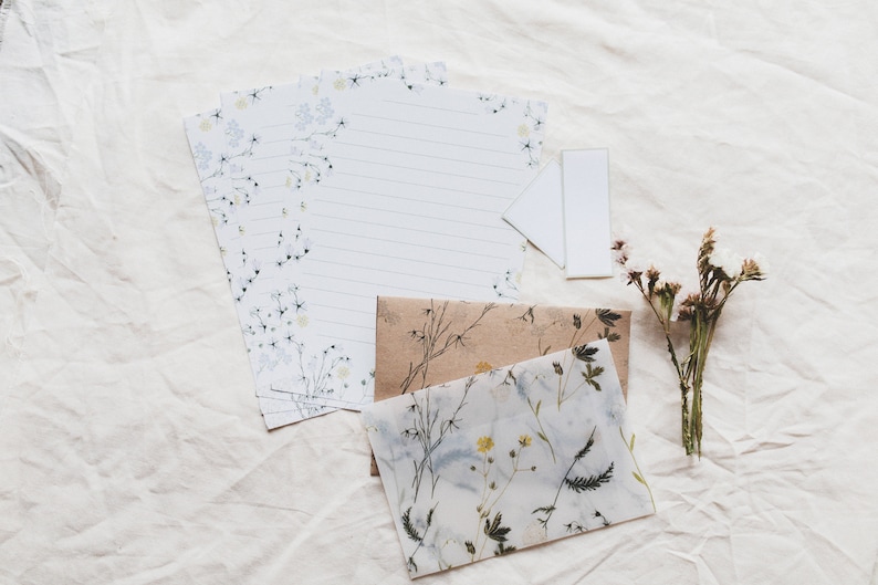 May include: A set of floral stationery with a white envelope and a blank card. The stationery features a delicate floral pattern in shades of blue and white. The envelope is made of a translucent material with a floral pattern in shades of brown and white.