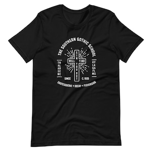 May include: Black t-shirt featuring a white graphic design of a cross with the text "The Southern Gothic School" surrounding it. The cross contains the words "Will Find You Out". The text "Since C. 1935 Grotesquerie + Decay + Perversion" is positioned below the cross.