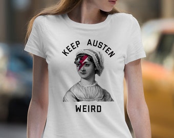 May include: White t-shirt with a black and white illustration of Jane Austen with a red lightning bolt over her eye. The text "Keep Austen Weird" is printed on the shirt.