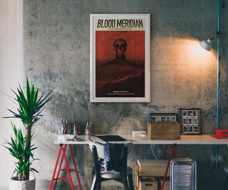 May include: A minimalist poster with a white frame and a red background. The poster features a skull with a red background and the text "Blood Meridian" and "The Evening Redness in the West" in black. The text "Cormac McCarthy" is in black at the bottom of the poster.