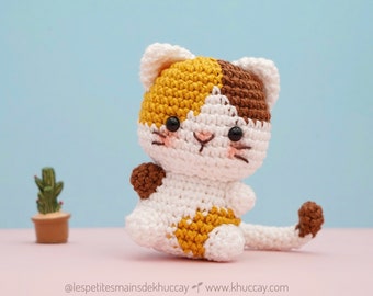 Peut inclure: Un jouet en crochet en forme de chat, réalisé avec du fil brun, blanc et jaune. Le chat a un visage mignon avec des yeux noirs et un nez rose.