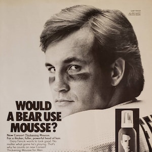 May include: A black and white photo of a man with a full head of hair. The man is wearing a jersey with the number 5 on it. The text "WOULD A BEAR USE MOUSSE?" is above the man's head. The text "New Consort Thickening Mousse. For a thicker, fuller, powerful head of hair. Gary Fencik wants to look good. No matter what game he's playing. That's why he counts on new Consort Thickening Mousse for Men. It literally makes hair look and feel thicker. Adds powerful body. And gives control, without looking stiff or phony. Just foam it out and massage it in after you shampoo. Style. Then stand back. Consort makes a real guy look real good." is below the man's head. The text "GROOMING GEAR FOR REAL GUYS. CONSORT." is at the bottom of the image. A can of Consort Styling Mousse for Men is in the lower right corner of the image.
