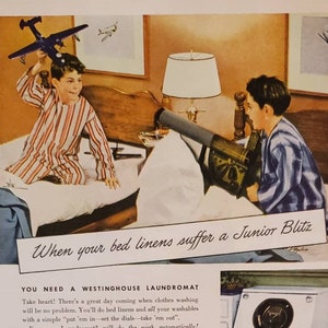 Puede incluir: Un anuncio vintage para la lavadora automática Westinghouse Laundromat. El anuncio presenta a dos niños en pijama jugando con aviones de juguete en un dormitorio. El texto dice "Cuando tus sábanas sufren un Blitz junior, necesitas un Westinghouse Laundromat". El anuncio también presenta una foto del Laundromat, una lavadora blanca con una gran ventana de vidrio.