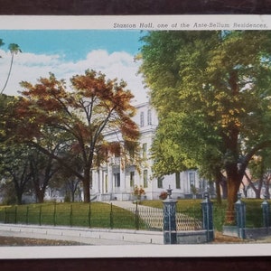 Puede incluir: Una postal antigua que representa Stanton Hall, una de las residencias Antebellum de Natchez, Mississippi. La postal muestra una gran casa blanca con un césped verde y árboles en frente.