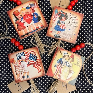 May include: Set of four vintage-style patriotic wooden ornaments. Each square ornament features a different illustration of children and American flags. The ornaments are strung with twine and red wooden beads, perfect for Independence Day.