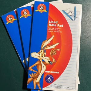 May include: A stack of Looney Tunes lined note pads. The pads feature a blue and red design with the Looney Tunes logo and an image of Wile E. Coyote. The page size is 3 3/8" x 6 3/4".
