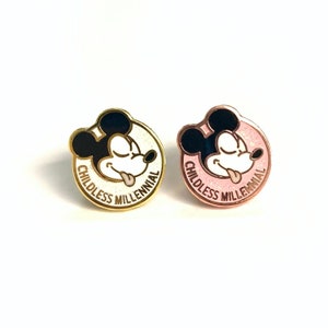 May include: Two enamel pins featuring a cartoon Mickey Mouse with the text "Childless Millennial" around the edge. One pin has a gold finish and a white background, while the other has a rose gold finish and a pink background.