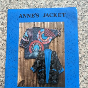 May include: A blue and white sewing pattern booklet with the title "Anne's Jacket" and the text "A Quilter's Wardrobe" and the number "8012". The cover features a photo of two jackets, one with a colorful patchwork design and the other with a black and blue checkered design.
