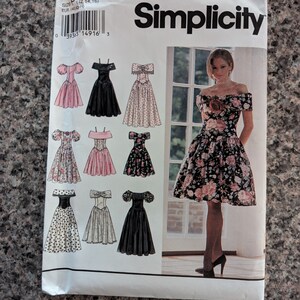 May include: Simplicity sewing pattern 8804 featuring various off-the-shoulder dress designs. The pattern includes illustrations of dresses in different colors and patterns, including floral and polka dot prints. The Simplicity logo is prominently displayed.