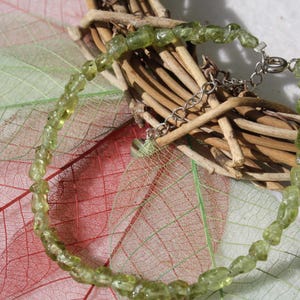Pode incluir: Um bracelete de pedras preciosas verdes com um fecho de prata. O bracelete é feito de pequenas contas de forma irregular.