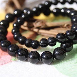 May include: Two black beaded bracelets made of round, shiny black beads.