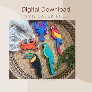 May include: A digital download SVG laser file featuring five colorful animal cutouts: a blue lobster, an orange crab, a red and yellow parrot, a blue and yellow macaw, and a black toucan with a multicolored beak, all arranged on a woven tray.