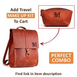 May include: A cognac-colored leather backpack with a flap closure, a metal clasp, and a letter M monogram featuring floral details. Included is a matching leather makeup pouch with the same letter M monogram and floral design.