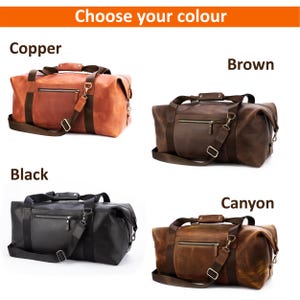 May include: Four duffel bags labelled Copper, Brown, Black, and Canyon. Each bag features a horizontal zippered front pocket, dark brown fabric straps, a top handle, and a detachable shoulder strap with metal hardware and a padded shoulder section.