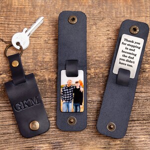 May include: Three dark navy leather keychains with brass snap buttons. One keychain features the embossed letters GKM and a silver key. Another displays a color photograph of two people. The third shows the text: Thank you for stepping in and becoming the dad you didn't have to.