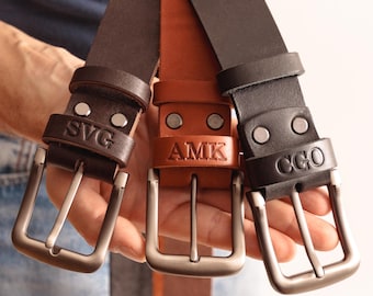 May include: Three leather belts in dark brown, tan, and black, each featuring a metal buckle and two silver-toned rivets. The belts are embossed with the personalised initials SVG, AMK, and CGO respectively on the leather keeper loop.