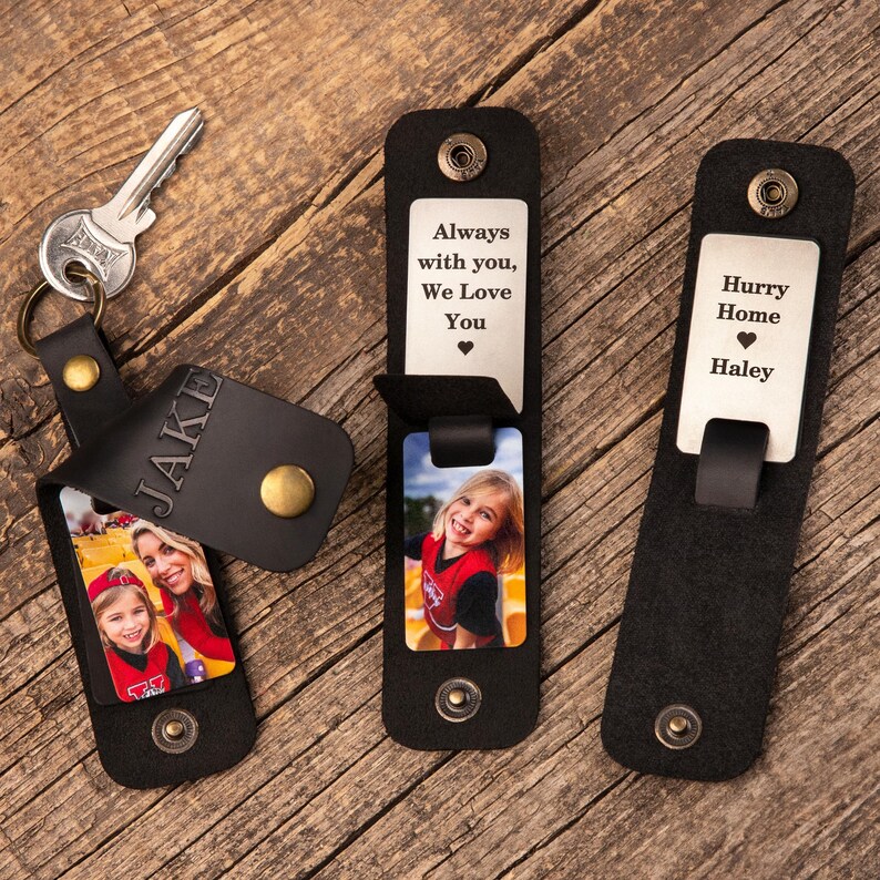 May include: Three black leather keychains with brass snaps. One keychain holds a silver key and features the name JAKE embossed on the leather flap, revealing a photo of a child and adult. Two others show metal plates with text and photos.