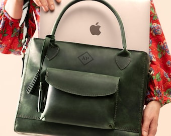 May include: A dark green leather tote bag featuring a front flap pocket, two top handles, and a decorative tassel. The bag is embossed with a diamond-shaped logo containing the letters KP. A silver laptop is partially visible inside the bag.