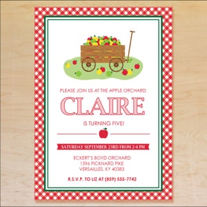 May include: A red and white checkered invitation for a birthday party at an apple orchard. The invitation features a cartoon illustration of a red wagon filled with apples and the text "PLEASE JOIN US AT THE APPLE ORCHARD CLAIRE IS TURNING FIVE! SATURDAY SEPTEMBER 23RD FROM 2-4 PM ECKERT'S BOYD ORCHARD 1396 PICKNARD PIKE VERSAILLES, KY 40383 R.S.V.P. TO LIZ AT (859) 555-7742"