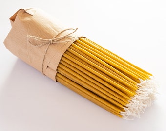 May include: A bundle of yellow beeswax candles wrapped in brown paper and tied with twine. The candles are arranged in a neat stack and have a natural, rustic look.