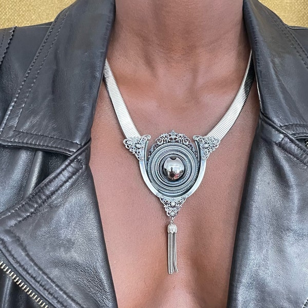 Ermani Bulatti 1990's- Collier ras de cou, dentelle de métal, imposant cabochon de verre imitant l'hématite, pompon de chainettes- Signé