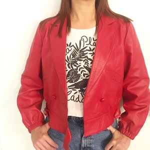 1980's- Veste courte en cuir d'agneau rouge- Croisée, cintrée, deux boutons et deux sangles sur les cotés- Très belle qualité, ultra légère!