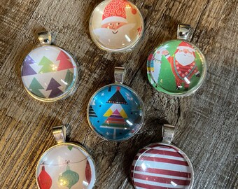 May include: Six Christmas-themed glass ornaments with silver metal frames and hanging loops. The ornaments feature a variety of designs, including a Santa Claus, a Christmas tree, and a geometric pattern.