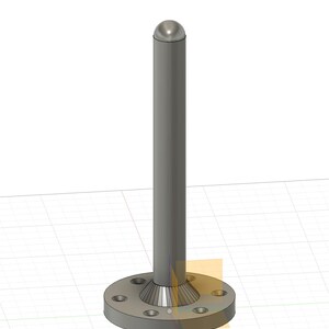 May include: A silver metal post with a rounded top and a base with a flange and six holes. The post is standing on a gridded surface.