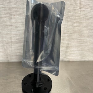 May include: Black metal base with a black metal rod and a black ball on top. The base has a circular shape with a textured surface. The rod is smooth and cylindrical. The ball is smooth and spherical. The base is attached to the rod with a threaded connection. The rod is attached to the ball with a threaded connection. The base has a diameter of approximately 7.6 cm. The rod is approximately 15.2 cm long. The ball is approximately 2.5 cm in diameter.