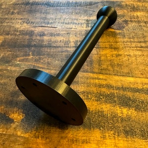 May include: Black plastic stand with a round base and a cylindrical post with a rounded top.