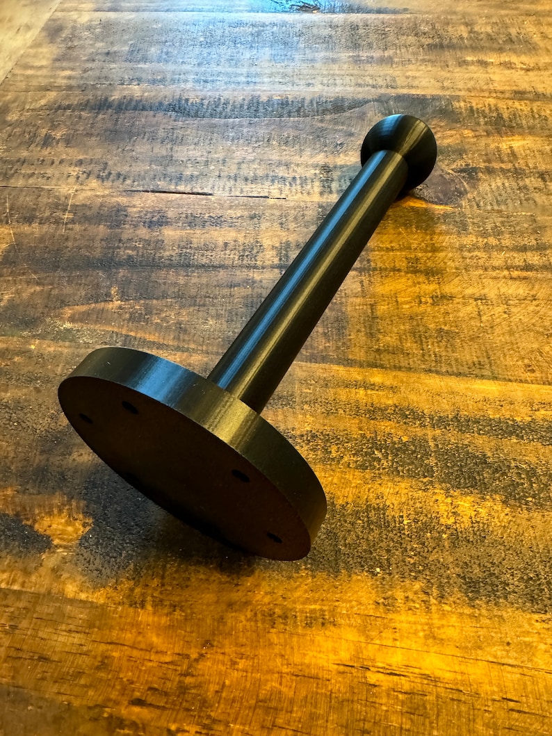 May include: Black plastic stand with a round base and a cylindrical post with a rounded top.