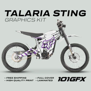 May include: White and purple graphic kit for a Talaria Sting electric dirt bike. The kit includes a full-coverage design with the Fox Racing logo and "Race Line Edition" text.