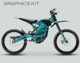 May include: A teal and black Surron Light Bee X electric motorcycle with Red Bull graphics. The motorcycle has a black seat, black wheels, and a black chain. The graphics are printed on the side panels, the front fender, and the rear fender. The text "SURRON LIGHT BEE X" and "GRAPHICS KIT" are printed in white on a black background at the top of the image. The text "101GFX" is printed in black on a white background at the bottom of the image.