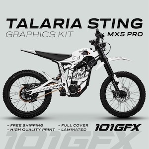 Peut inclure: Kit graphique Talaria Sting MX5 Pro blanc et noir avec la marque Red Bull. Le kit comprend une couverture complète et une impression laminée de haute qualité. Le texte "TALARIA STING GRAPHICS KIT MX5 PRO" est affiché en haut.