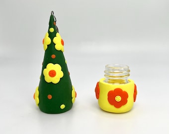 May include: A green cone-shaped bottle stopper with yellow and orange flowers and orange dots. The stopper is attached to a silver chain. A clear glass bottle with a yellow and orange flower design is also shown.
