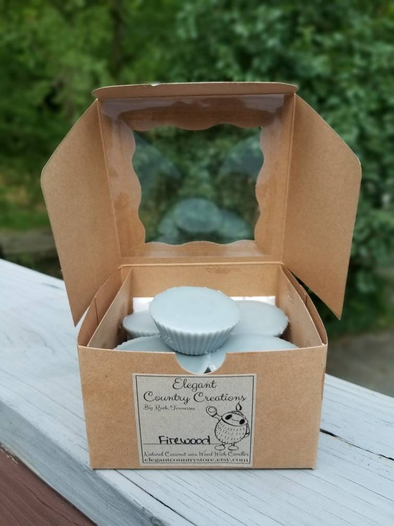 May include: A brown cardboard box with a clear plastic window, containing a stack of light blue wax melts. The box has a label that reads "Elegant Country Creations" and "Firewood".