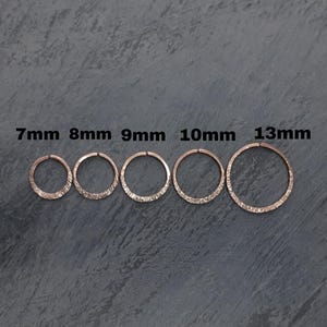 May include: Five rose gold hoop rings with a textured finish, arranged in a row from smallest to largest. The rings are labelled with their respective diameters of 7mm, 8mm, 9mm, 10mm, and 13mm, indicating the specific size for each individual hoop.