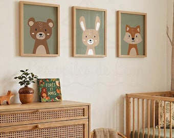 May include: Three rectangular framed wall art prints featuring stylized illustrations of a brown bear, a tan rabbit, and a brown fox on a sage green background, displayed in light wood frames on a wall above a wooden dresser.