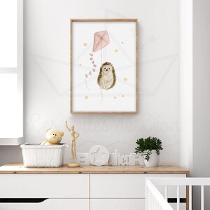 May include: A watercolour illustration of a hedgehog holding a pink kite with yellow stars in the background. The illustration is framed in a light wood frame.