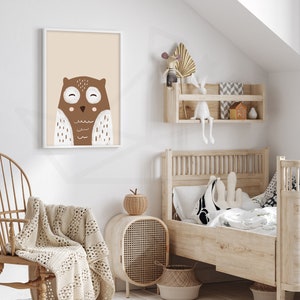 May include: A brown and white owl illustration in a white frame hanging on a white wall. The owl has large eyes and a small beak. The illustration is on a light beige background.