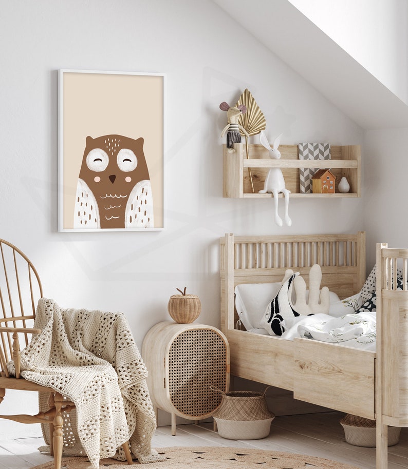May include: A brown and white owl illustration in a white frame hanging on a white wall. The owl has large eyes and a small beak. The illustration is on a light beige background.