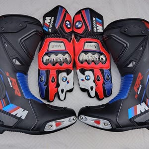 May include: A pair of black, red, and blue motorcycle boots and matching gloves featuring the BMW M1000 RR logo. The boots have protective plates and the gloves include knuckle armor, BMW branding, and the text M1000 RR on the cuffs and fingers.