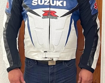 May include: A white and blue leather motorcycle jacket with black accents. The jacket has a Suzuki logo and a red and white racing stripe on the chest.