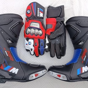 May include: A pair of black, red, and blue motorcycle boots featuring the S 1000 RR logo and M branding, alongside a pair of matching motorcycle gloves with BMW M 1000 RR text, metallic knuckle protectors, and the BMW logo on the fingers.