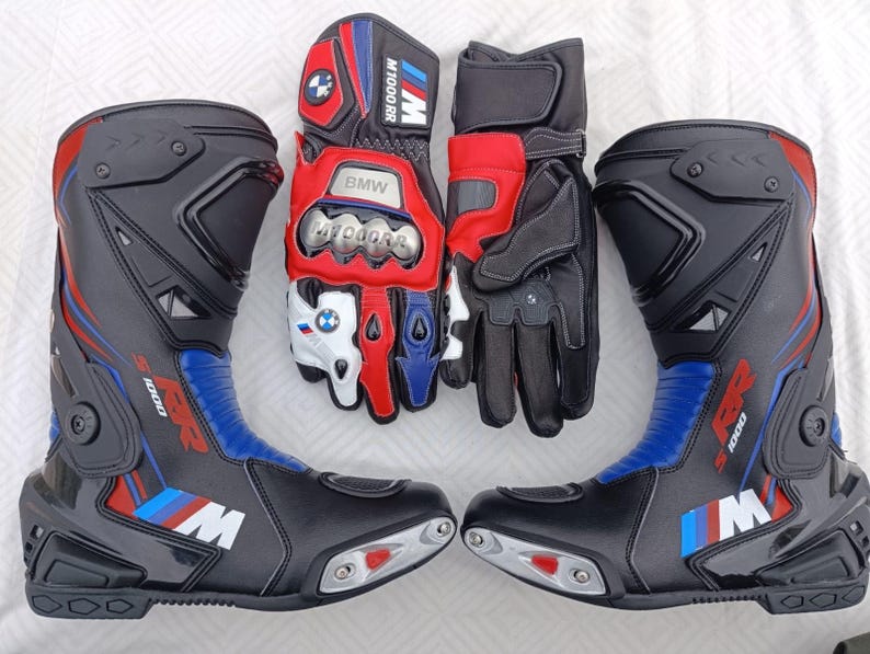May include: A pair of black, red, and blue motorcycle boots featuring the S 1000 RR logo and M branding, alongside a pair of matching motorcycle gloves with BMW M 1000 RR text, metallic knuckle protectors, and the BMW logo on the fingers.