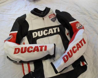 May include: White, black, and red Ducati motorcycle racing jacket. The jacket features the Ducati logo in large, bold letters across the chest and sleeves. The jacket has a zipper closure and a stand-up collar.