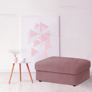 May include: A dusty rose colored ottoman with a square top and a rectangular base. The ottoman is sitting on a light wood floor in front of a white wall with a pink and white geometric print.