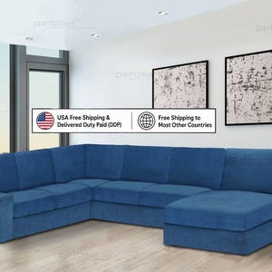 Op de afbeelding: Een grote, blauwe L-vormige hoekbank met een chaise longue aan de rechterkant. De bank is bekleed met een effen, blauwe stof en heeft brede armleuningen en meerdere rugkussens, wat zorgt voor een ruime zitgelegenheid.