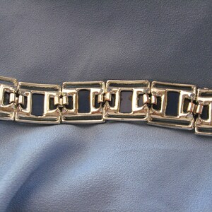 May include: A silver bracelet with a chain link design and dark blue enamel accents.